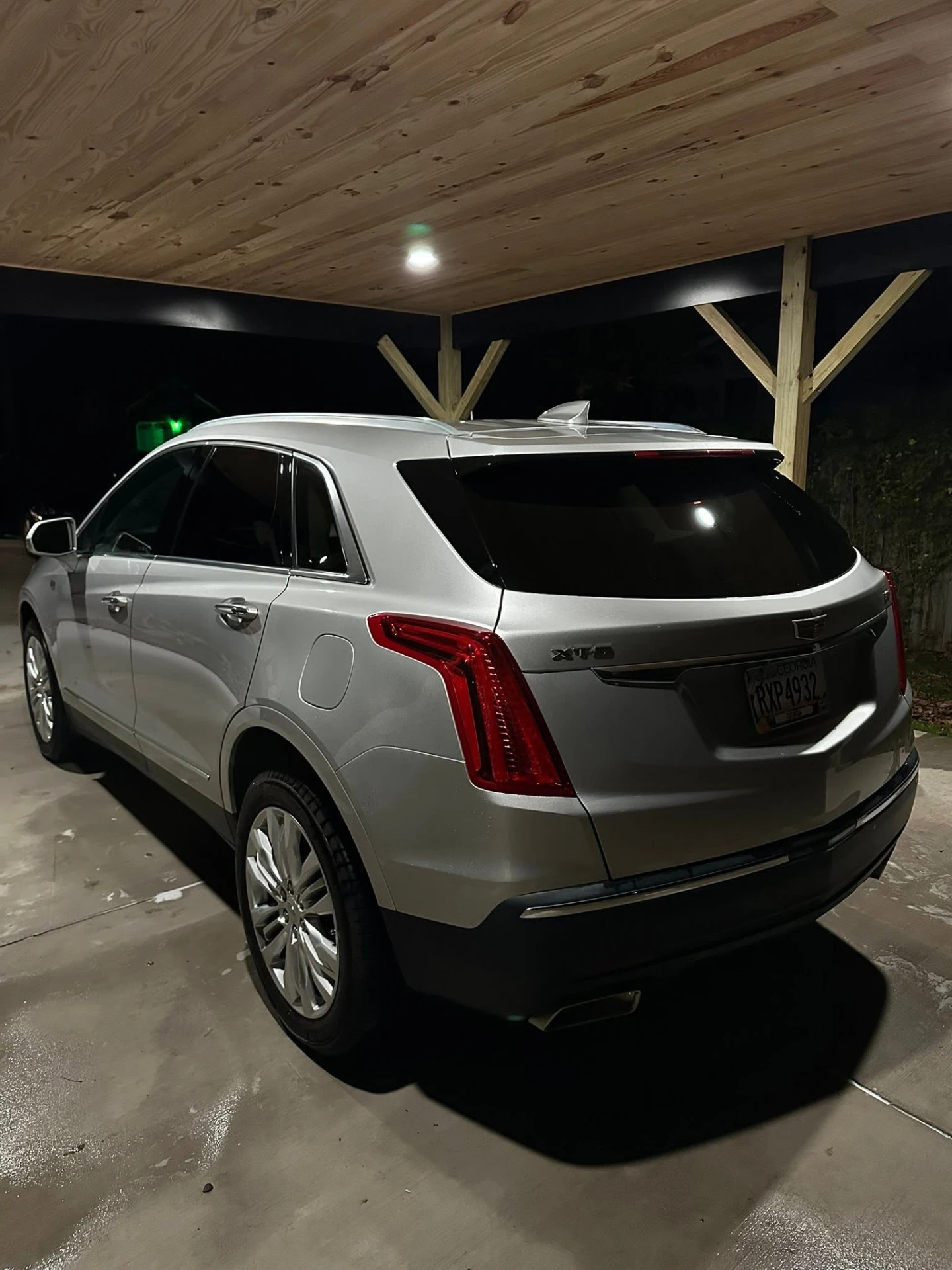 Silver Cadillac XT5 rear quarter after detail under carport at night